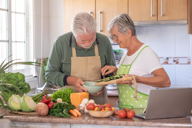 Attractive senior couple working together in home kitchen preparing vegetables and zucchini Elderly smiling couple enjoying healthy lifestyle