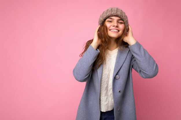 Attractive smiling happy young brunet woman standing isolated over colorful background wall wearing everyday stylish outfit showing facial emotions looking at camera