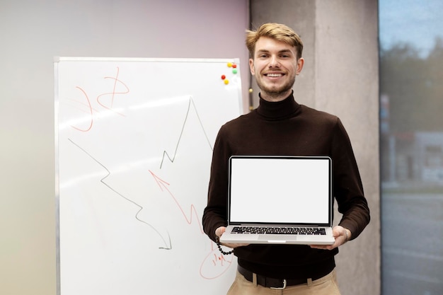 Attractive smiling man holding laptop with blank screen Successful young businessman