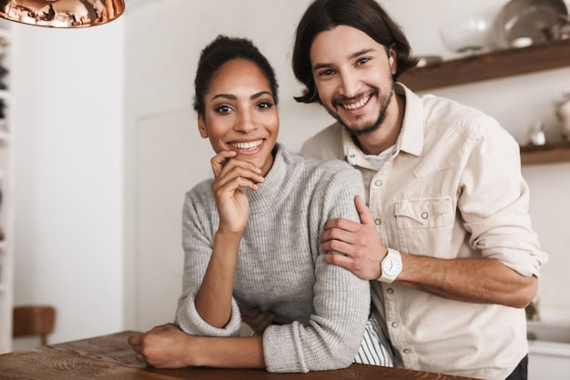 Attractive smiling man and pretty african american woman leaning on table joyfully 