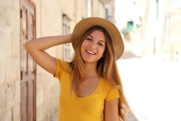 Attractive smiling young tourist woman with straw hat on a sunny day of summer on holidays