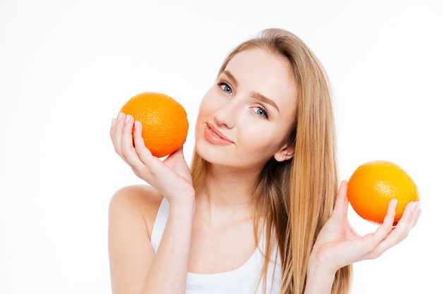 Attractive smiling young woman posing with two fresh oranges over white background