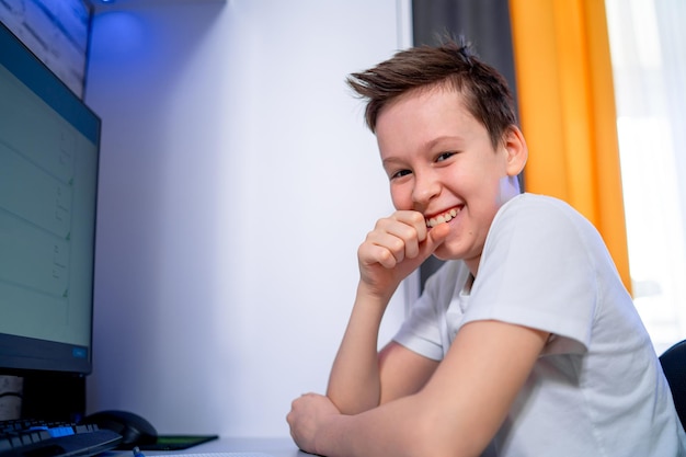 Attractive smilling boy having fun with computer. Child is playing a game on a computer.