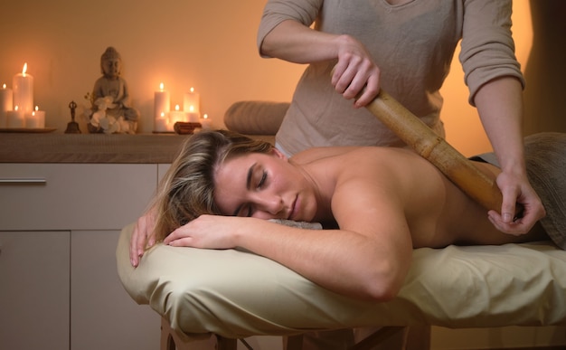 Attractive Spanish woman getting a relaxing massage with a bamboo stick in a wellness center