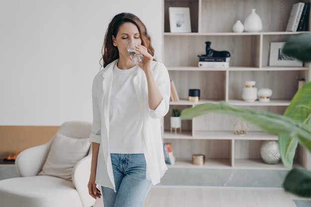 Attractive spanish woman is drinking clean water at home Purified water for healthy lifestyle