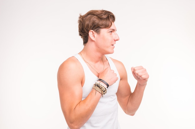 An attractive sporty man shows his biceps and smiling on white