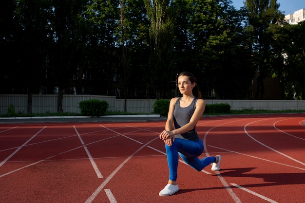 Attractive sporty woman stretching before running at the stadium. Space for text