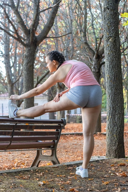 Attractive sporty woman warming up in a park Beautiful girl doing warmup exercises in a park