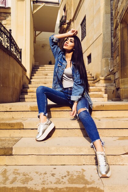 Attractive stylish black-haired girl posing against the colorful architecture of Baku