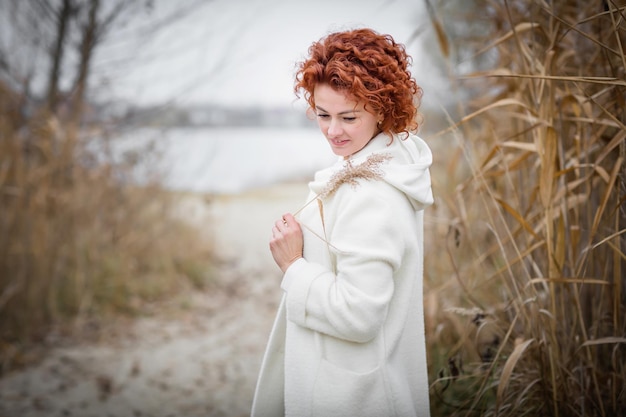 Attractive stylish woman holding dry reed walking in park