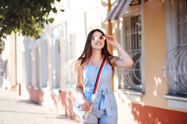 Attractive stylish woman is spending time outdoors in the street. Summer time, vacation or holiday.