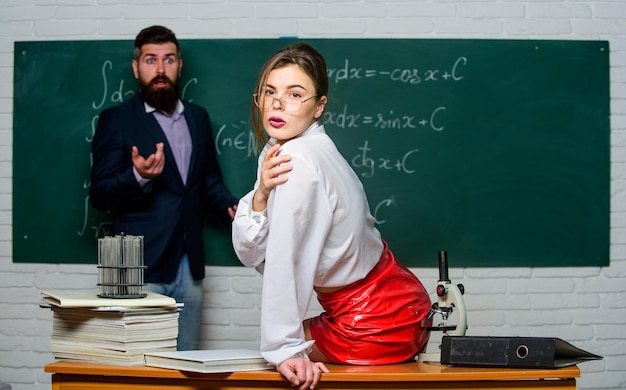 Attractive teacher in leather skirt Cheeky teacher Impudent student Flirting with colleague Science is sexy Sexy girl sit table while man stand chalkboard Everyone dreaming about such teacher