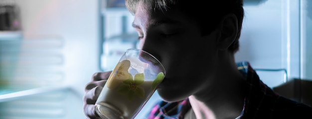 Attractive teen drinking cool milk from the fridge at night