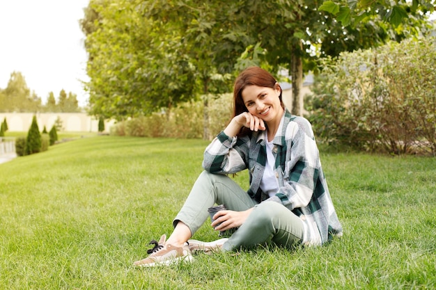 Attractive woman in autumn casual clothes sitting in the park for a walk