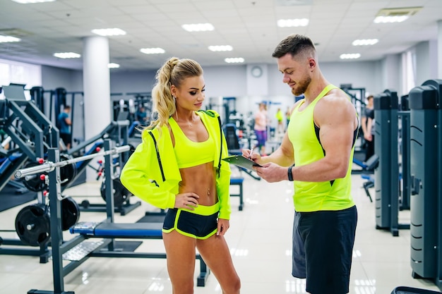 Attractive woman and handsime man in modern gym Young couple is working out at gym