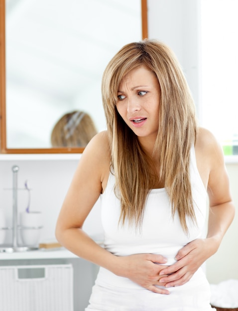 Attractive woman having a stomachache in the bathroom