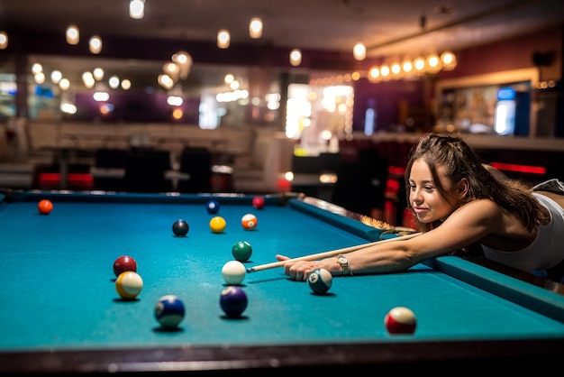 Attractive woman hold cue and playing billiards