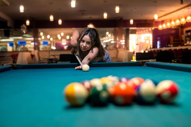 Attractive woman hold cue and playing billiards