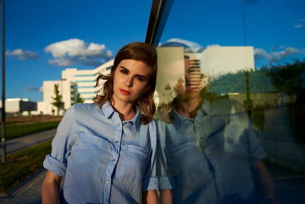 Attractive woman leaning on a glass, her reflection is projected on the glass