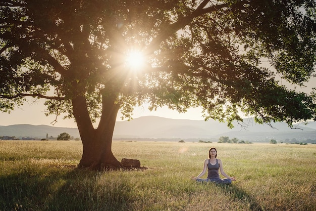 Attractive woman practices yoga in nature in summer