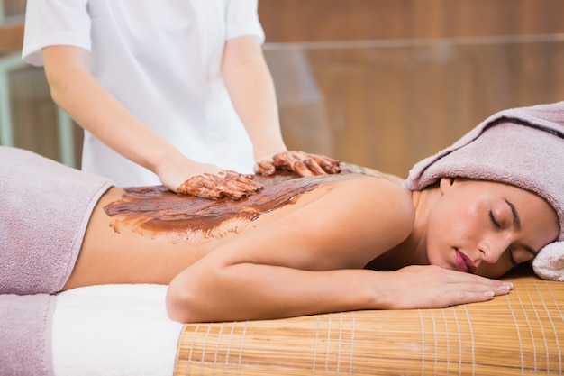 Attractive woman receiving chocolate back mask at spa center