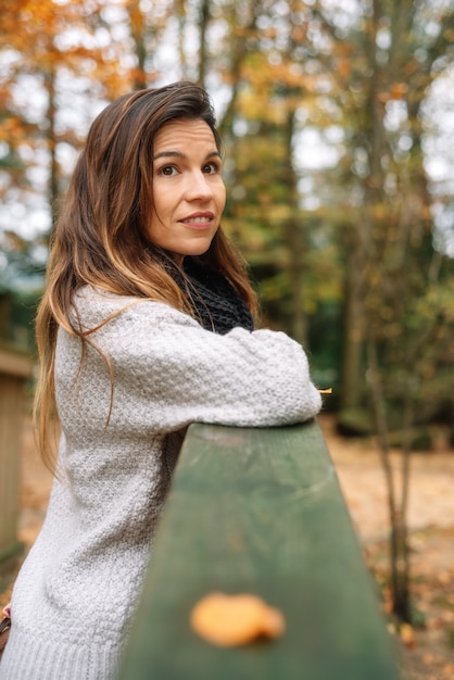 Attractive woman, relaxed in a park In autumn surrounded by colorful leaves looking to the trees pensively.