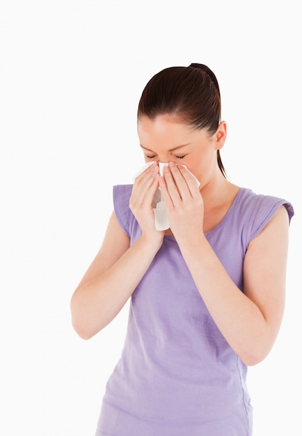 Attractive woman sneezing while standing