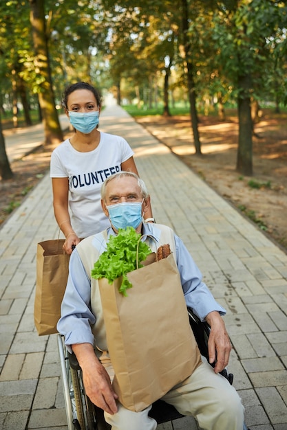 Attractive woman spending time with disabled older male in the outdoors