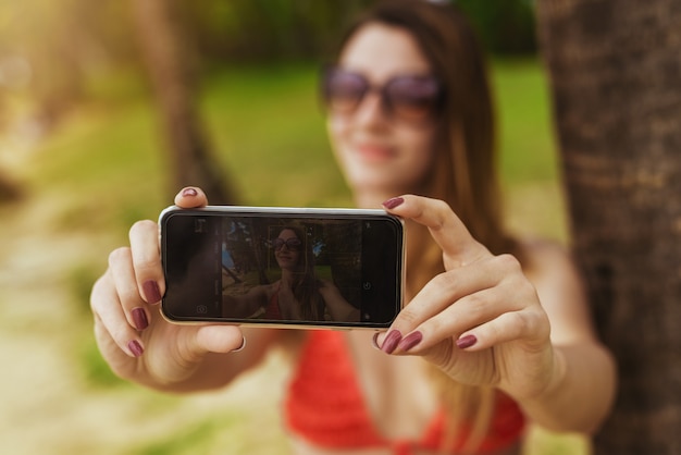 Attractive woman taking picture of herself relaxing at beach