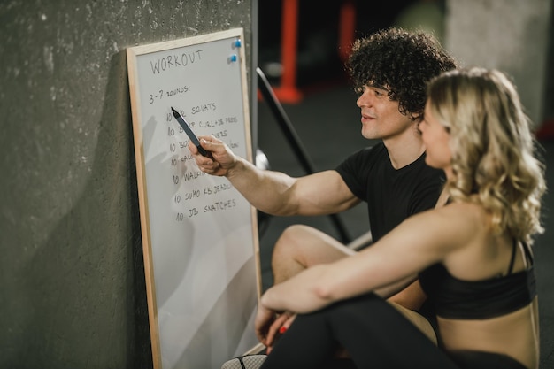 Photo an attractive woman talking about exercise plan with her personal trainer at the gym.