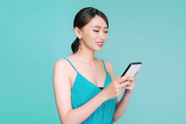 Attractive woman using text messaging feature on her portable device in studio