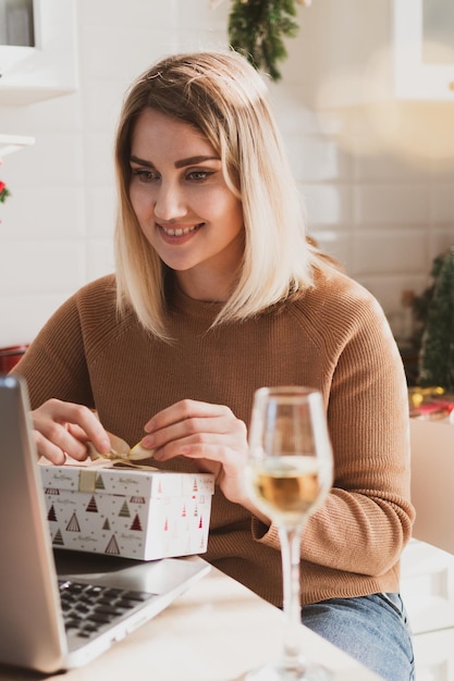 Attractive woman video chatting on laptop for christmas holidays and packing gifts