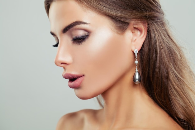 Attractive Woman wearing Silver Earrings with Pearls and Diamond Female Face Closeup