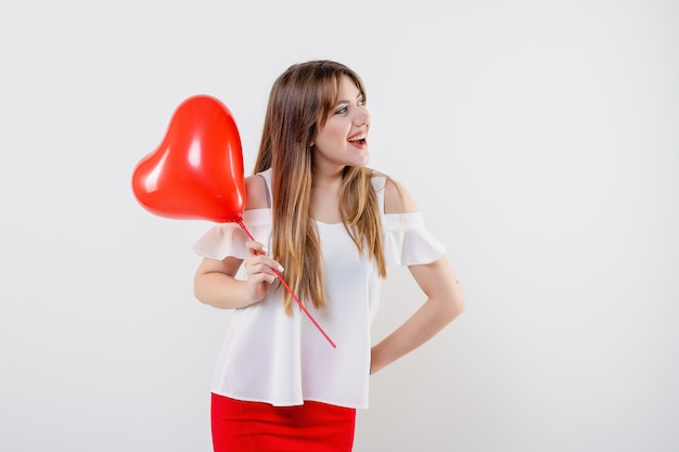 Attractive woman with red heart shaped balloon isolated