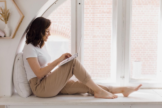 Attractive woman working on laptop seated at desk in cozy living room businesswoman sit at workplace...