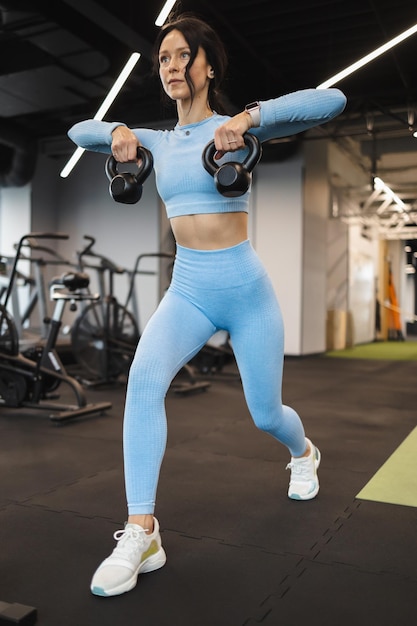 Attractive woman working out with kettlebell at the gym