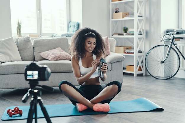 Attractive young African woman working out and smiling while making social media video