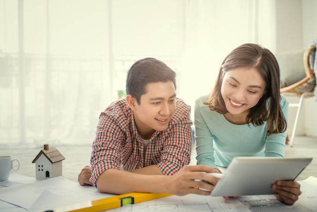 Attractive young asian adult couple looking at house plans.