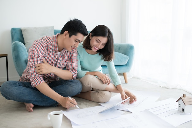 Attractive young asian adult couple looking at house plans.