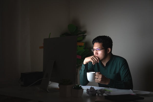 Attractive young asian man drinking coffee sitting on desk table