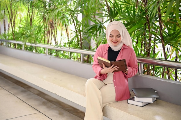 An attractive young Asian Muslim female college student reading a book