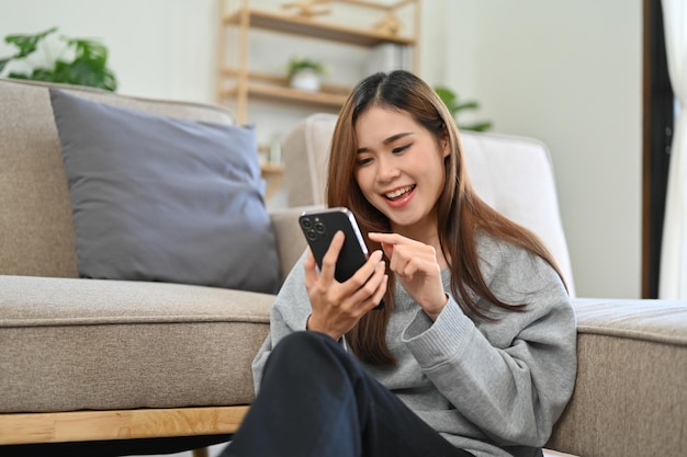 Attractive young Asian woman enjoys chatting with her friends on her smartphone