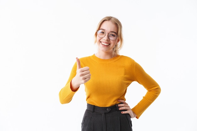 Attractive young blonde woman wearing sweater standing isolated over white wall, thumbs up