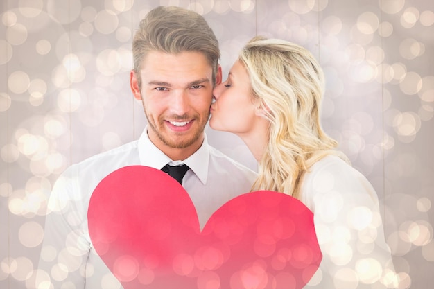 Attractive young couple holding red heart against light glowing dots design pattern