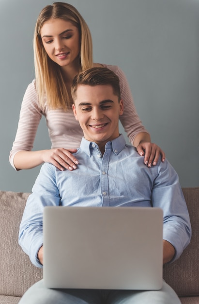 Attractive young couple is using a laptop and smiling