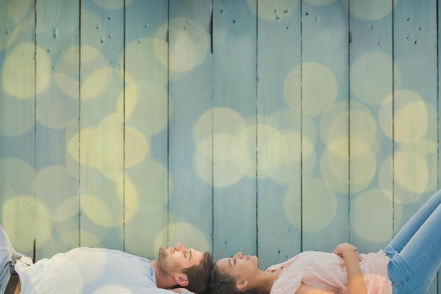 Attractive young couple lying down against blurry yellow christmas light circles