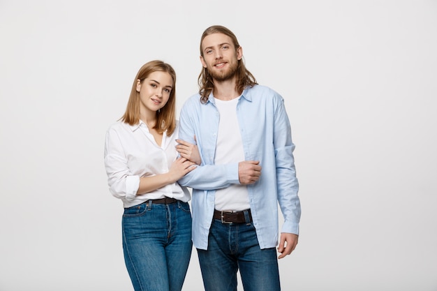 attractive young couple smiling for the camera while holding arm to arm. 