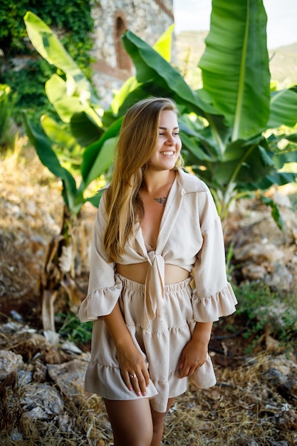 Attractive young fair-skinned woman stands near banana trees in tropical park