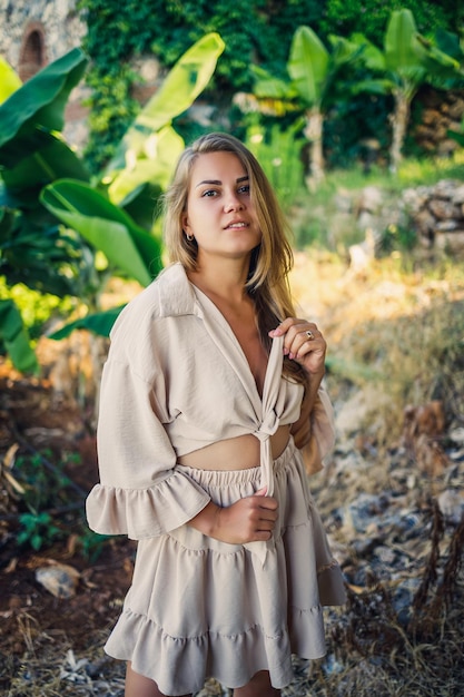 Attractive young fairskinned woman stands near banana trees in tropical park