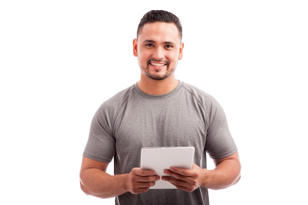 Attractive young fitness coach using a tablet computer on a white background